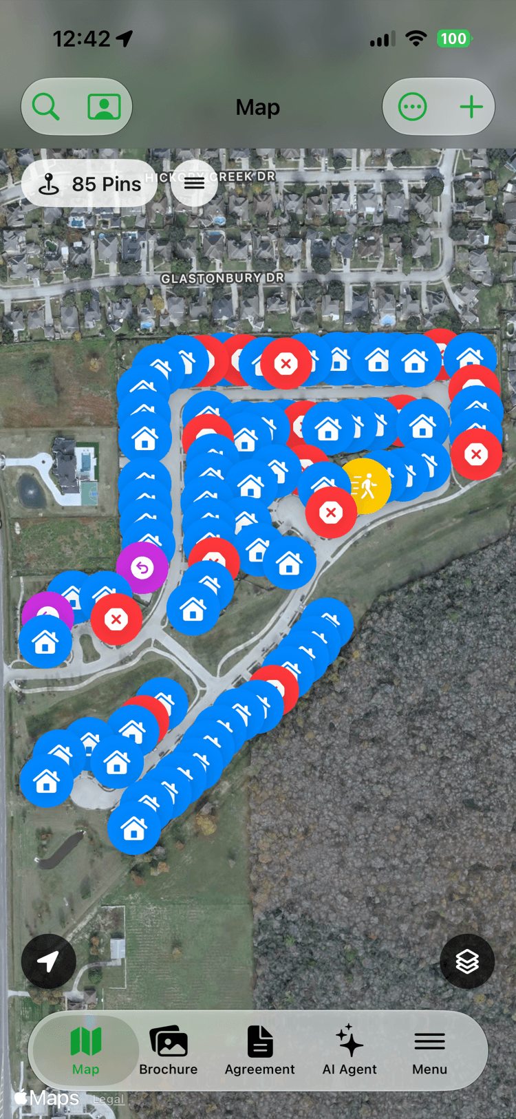 A satellite knocking map of a neighborhood covered in color-coded pins — blue for houses worked, red for not interested, yellow for not home — with a counter reading 85 pins.